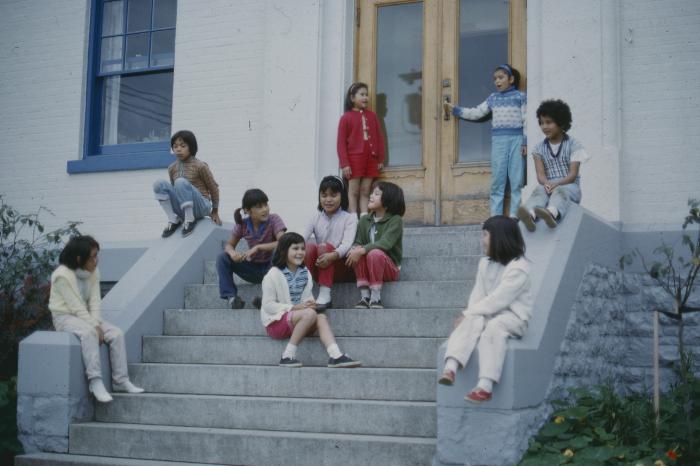 [Children seated by the front steps]