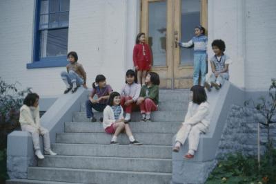 [Children seated by the front steps]