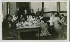 [Principal Ferrier and two staff members supervising students in the dining hall at dinner time, Brandon Institute]