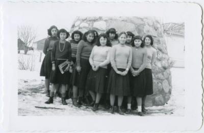 C.G.I.T. girls (not in uniform) in front of the cairn, Round Lake Residential School, Sask.