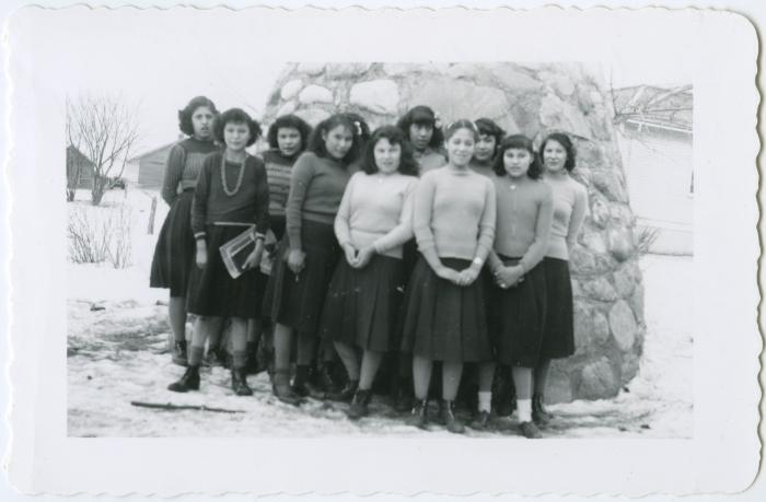 C.G.I.T. girls (not in uniform) in front of the cairn, Round Lake Residential School, Sask.
