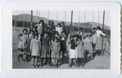 Girls with their dress-up hats at the swings on their playground, Round Lake, Sask.