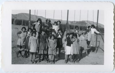 Girls with their dress-up hats at the swings on their playground, Round Lake, Sask.