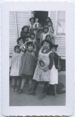 Mrs. Card and girls with their dress-up hats at their playroom door, Round Lake Residential School, Sask.