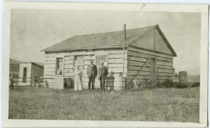 The old school house, now used as woodshed : Mrs. Steinhauer, Rev. E.R. Steinhauer and Rev. Arthur Barner in foreground, Morley Alta.