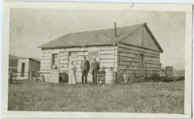 The old school house, now used as woodshed : Mrs. Steinhauer, Rev. E.R. Steinhauer and Rev. Arthur Barner in foreground, Morley Alta.