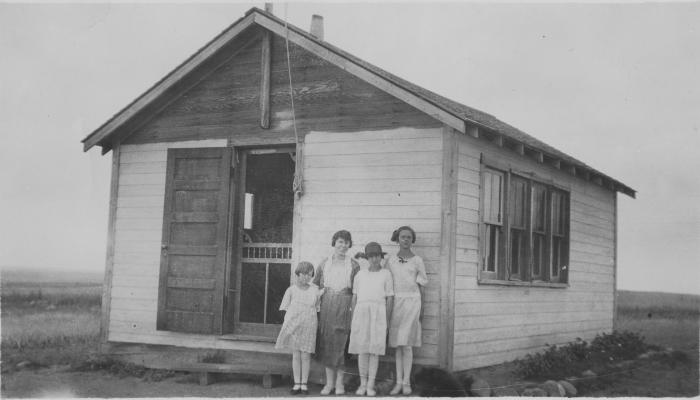 Four children outside a one room school house