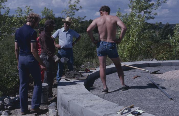 Elder Art Solomon, who is supervising the stone work on cairn, talks with some of the volunteers on the site, who are working on the construction