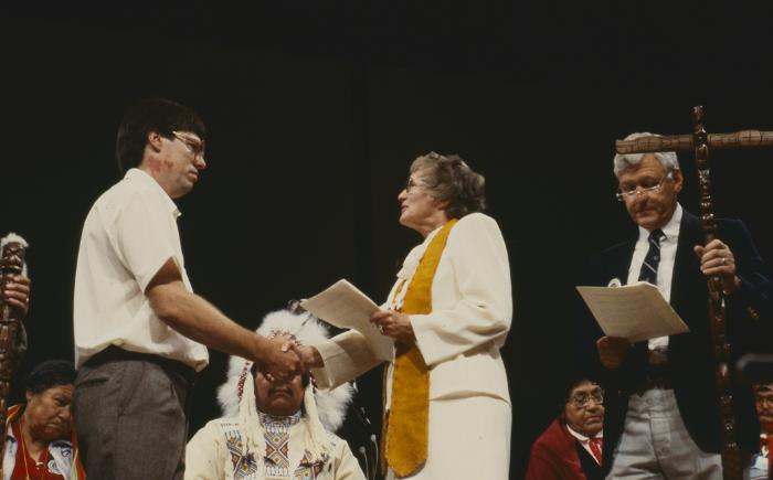 Anne Squire shaking hands with Alf Dumont on platform, after the constitution of ANCC and covenanting service, at the 32nd General Council