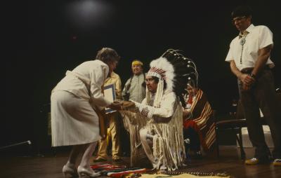 Floyd Steinhauer makes presentation to Anne Squire. Murray Whetung holds the framed Native apology, while delegates of ANCC stand with them on platform