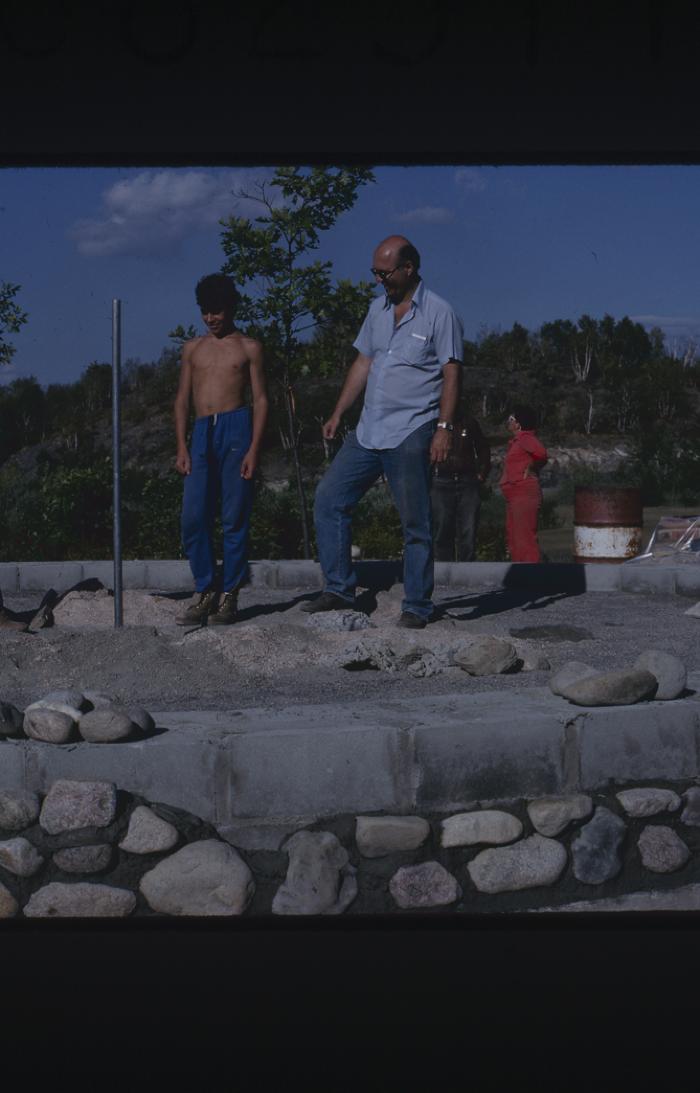 In work attire, men stand at the site of the cairn