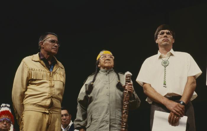 Alf Dumont, Gladys Taylor and Murray Whetung standing on platform at the 32nd General Council after the constitution and covenanting service.