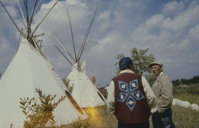 Moses Wood and Gordon Berens standing chatting in front of the tepees just erected the afternoon of General Council before the formal apology to the Native people by the United Church.