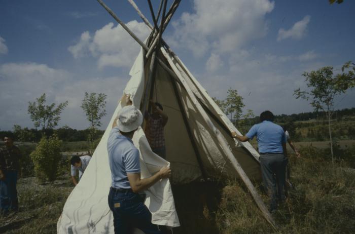 Alf Dumont erecting the teepees during the afternoon of General Council, on ground adjacent (part of) the University in Sudbury, which is built on traditional native land.
