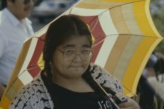 April Reid holds umbrella protects herself from the hot sun waiting for the gathering and the formal apology of the 31st General Council to the Native people.
