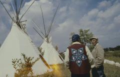 Moses Wood and Gordon Berens standing chatting in front of the tepees just erected the afternoon of General Council before the formal apology to the Native people by the United Church.