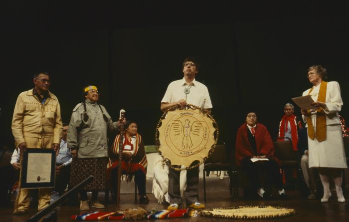 Alf Dumont holding the symbol of the ANCC, speaking to the delegates to the 32nd General Council at the constitution of the ANCC and covenanting service.