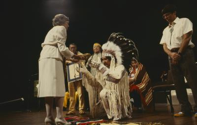 Floyd Steinhauer makes presentation to Anne Squire. Murray Whetung holds the framed Native apology, while delegates of ANCC stand with them on platform